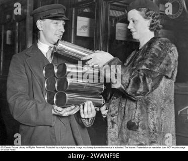 Per tenersi al caldo. Un conduttore sul treno da Londra in direzione nord consegna container con acqua riscaldata. Quando si tiene il letto durante il viaggio, aiuta a mantenersi al caldo. Una donna passante ne prende una. 1931 Foto Stock