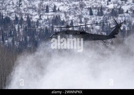 Snow prende il via mentre un elicottero UH-60L Black Hawk della Guardia Nazionale dell'Alaska decolla mentre supporta l'addestramento con il carico di imbracatura presso l'aeroporto Bryant Army, Joint base Elmendorf-Richardson, 28 febbraio 2024. I soldati dell'esercito degli Stati Uniti dell'Alaska Army National Guard Aviation Battalion hanno condotto l'addestramento con le fionde per migliorare la loro capacità di operare nell'ambiente duro dell'Alaska. (Alaska National Guard Foto Stock