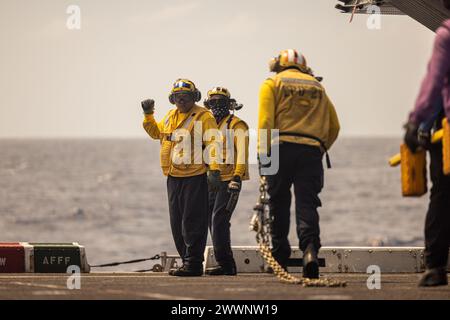 US Navy Aviation Boatswain's Mate (Handling) 3rd Class Alex Oros, Left, nativo della California assegnato al bacino di trasporto anfibio USS Somerset (LPD 25), afferma che i cunei e le catene sono stati rimossi da un aereo durante le operazioni di volo di routine a bordo del Somerset mentre era in corso nel Mar delle Filippine, 15 febbraio 2024. Somerset e gli elementi imbarcati della 15a MEU stanno conducendo operazioni di routine nella 7a flotta degli Stati Uniti. La 7th Fleet è la più grande flotta numerata della Marina degli Stati Uniti, e interagisce regolarmente e opera con alleati e partner nel preservare una a libera Foto Stock