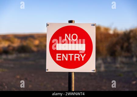 Primo piano su un cartello SENZA INGRESSO e fuori fuoco sullo sfondo di un paesaggio semi-desertico. Foto Stock