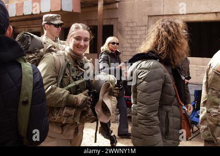 2nd Lieutenant Eliza Ewing, 2nd Squadron, 11th Armored Cavalry Unit, Operations Officer, cammina con gli ospiti del Community Box Tour attraverso un mercato pieno di giocatori di ruolo che agiscono come civili sul campo di battaglia (COBS) 2 febbraio 2024, presso il National Training Center, Fort Irwin, California. Le truppe di Ewing mostrarono le loro abilità di combattimento durante una battaglia simulata rimessa in atto per gli ospiti del tour e poi ospitarono un pranzo di pasti pronti da mangiare (MREs). Esercito Foto Stock