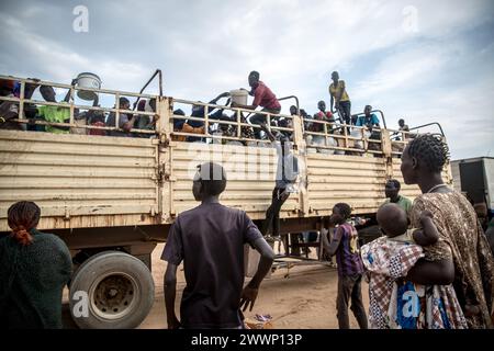 Renk, Sudan del Sud. 19 marzo 2024. Le persone in fuga dalla guerra sudanese sbarcano da un camion che li ha portati a Renk dal valico di frontiera di Joda nel Sudan meridionale. La maggior parte rimarrà nel centro di transito lì per una o due settimane prima di spostarsi in altre parti del paese. Circa 1.000 rimpatriati e rifugiati sudanesi attraversano ogni giorno il confine dal Sudan al Sudan meridionale. La guerra in Sudan, iniziata nell'aprile 2023, ha portato alla più grande crisi di sfollamento del mondo. Credito: SOPA Images Limited/Alamy Live News Foto Stock