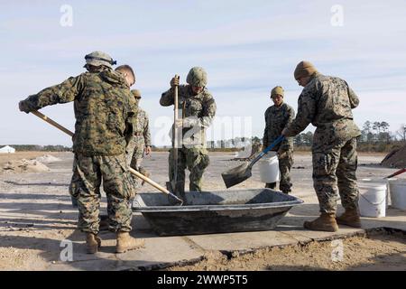 U.S. Marines con 8th Engineer Support Battalion, 2nd Marine Logistics Group e U.S. Navy Sailors con Naval Mobile Construction Battalion 1, mescola cemento per riempire un cratere sull'asfalto dell'aeroporto durante l'esercitazione Winter Pioneer 24, Marine Corps Outlying Field Oak Grove, North Carolina, 15 febbraio 2024. Gli ingegneri del corpo dei Marines degli Stati Uniti e la forza di costruzione della Marina degli Stati Uniti hanno utilizzato il Marine Corps Outlying Field Oak Grove per i Marines e i marinai per provare a creare e sostenere basi navali e di spedizione avanzate che contribuiscono alla consapevolezza del dominio marittimo. Corpo dei Marine Foto Stock