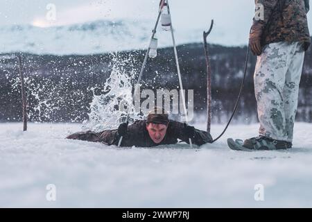 U.S. Navy Hospital Corpsman 3rd Class William Baldwin, un corpsman con Bravo Battery, 2nd Low Altitude Air Defense (LAAD) Battalion, 2nd Marine Aircraft Wing, utilizza pali da sci per tirarsi fuori dall'acqua durante un'esercitazione rompighiaccio in preparazione all'esercitazione Nordic Response 24 a Setermoen, Norvegia, 1 febbraio 2024. Exercise Nordic Response, precedentemente noto come Cold Response, è un evento di addestramento NATO condotto ogni due anni per promuovere le competenze militari in ambienti artici e per promuovere l'interoperabilità tra il corpo dei Marines degli Stati Uniti e le nazioni alleate. Corpo dei Marine Foto Stock