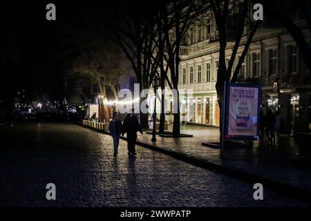 La gente cammina lungo la buia via Deribasovskaya, alla luce delle vetrine dei negozi alimentate dai generatori. Un massiccio attacco missilistico contro l'Ucraina avvenne nelle ore mattutine del 22 marzo 2024. Kharkiv, Zaporizhzhia, Kryvyi Rih, Khmelnytskyi, Poltava Oblast, Vinnytsia Oblast, Lviv Oblast, Ivano-Frankivsk Oblast, Mykolaiv Oblast, Odesa Oblast, l'Oblast' di Sumy e altre parti del paese furono sottoposte al fuoco di razzi da parte dell'esercito russo. La stazione idroelettrica Dnieper fu messa fuori servizio (otto missili colpiti; un filobus che trasportava civili che viaggiavano lungo la diga fu colpito; la seconda potenza u Foto Stock