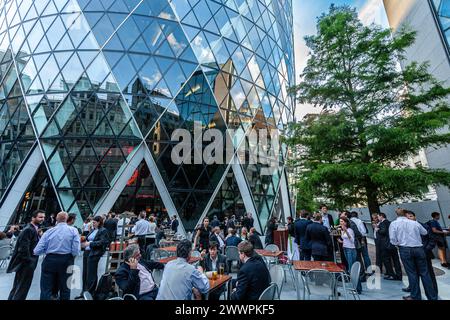 Edificio Gherkin nella City di Londra con gente seduta fuori Foto Stock