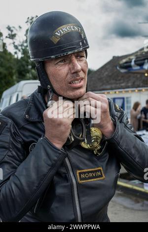 biker, caffè racer casco e occhiali di protezione sempre pronto. tondo su ragazzo casco di fissaggio. Foto Stock