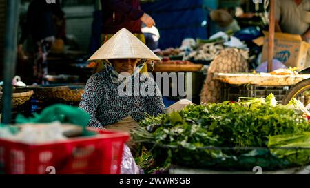 Donna anziana in cappello di paglia seduto al mercato Foto Stock