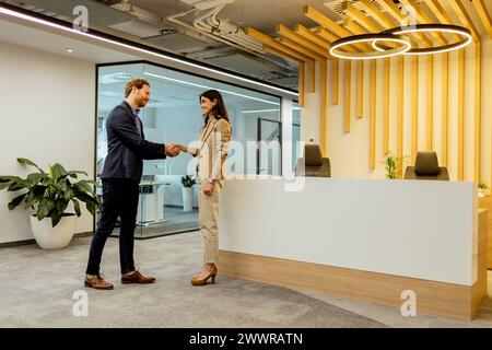 Due professionisti che scambiano saluti con una stretta di mano in un elegante ambiente d'ufficio Foto Stock