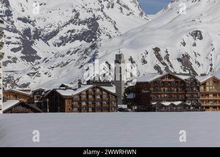 Il campanile della chiesa di Tignes le Lac, una stazione sciistica delle Alpi francesi, sorge sopra le strutture turistiche costruite in tradizionale stile chalet. Foto Stock