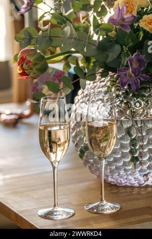 Due bicchieri da vino e fiori su una superficie di legno Foto Stock