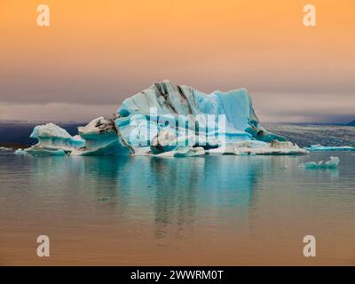 Iceberg blu nella laguna del ghiacciaio Jokulsarlon insera luce del sole rossa, Islanda Foto Stock