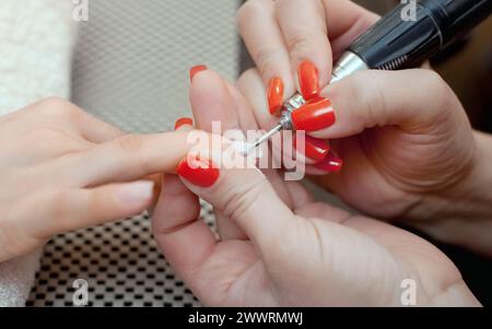 Il maestro della manicure seziona e attacca una forma di chiodo durante la procedura di estensione delle unghie con gel nel salone di bellezza. Assistenza professionale Foto Stock