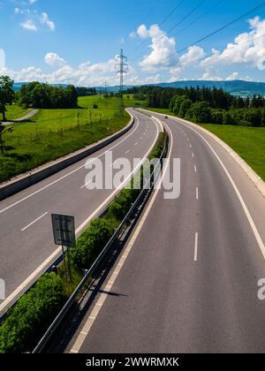 Autostrada larga a due linee con curva in giornata di sole Foto Stock