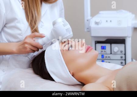 Il medico-cosmetologo effettua la procedura di crioterapia della pelle del viso di una bella e giovane donna in un salone di bellezza. Cosmetologia e professionale Foto Stock