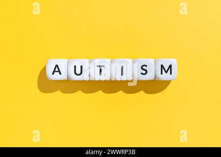 Parola di autismo su blocchi cubi bianchi isolati su sfondo giallo Foto Stock