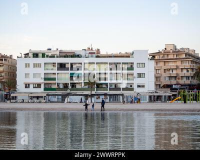 La gente su una spiaggia con edifici lontani, Mallorca, Spagna Foto Stock