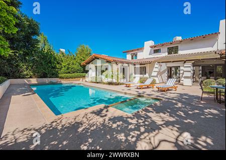 Piscina, sedie a sdraio e patio vicino a una casa Foto Stock