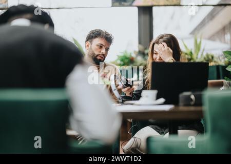 Incontro di lavoro informale in un accogliente caffè con due giovani professionisti impegnati in discussioni. Foto Stock