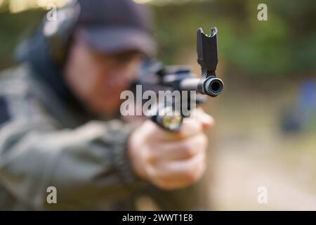 Un uomo ha in mano una pistola con una bandiera nera. L'uomo indossa una giacca verde e un cappello nero Foto Stock