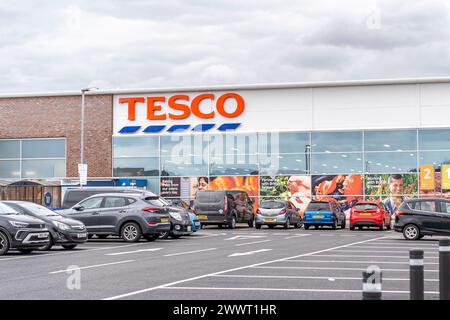 Vista esterna di un supermercato britannico Tesco con auto parcheggiate nel parcheggio esterno. Foto Stock