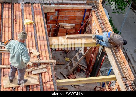 Gli operai edili sistemano i mattoni prima di versare la lastra del tetto. Fabbricazione della cassaforma in legno e installazione del rinforzo in acciaio. Foto Stock