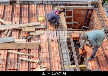 Gli operai edili sistemano i mattoni prima di versare la lastra del tetto. Fabbricazione della cassaforma in legno e installazione del rinforzo in acciaio. Foto Stock