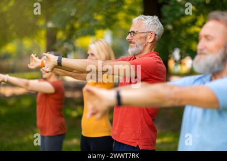 Gli adulti anziani partecipano all'esercizio di stretching, estendendo le braccia in avanti Foto Stock