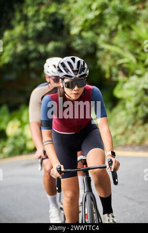 giovani donne asiatiche ciclisti in sella a un allenamento ciclistico su strada rurale Foto Stock