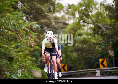 gruppo di giovani ciclisti professionisti asiatici che si allenano in bicicletta su strada rurale Foto Stock