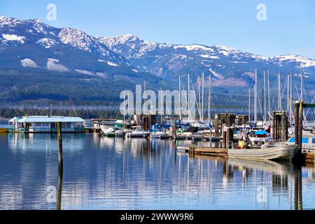 Le varie barche ormeggiate al Deep Bay Marina con riflessi luminosi nell'acqua dell'oceano e nelle montagne lontane Foto Stock