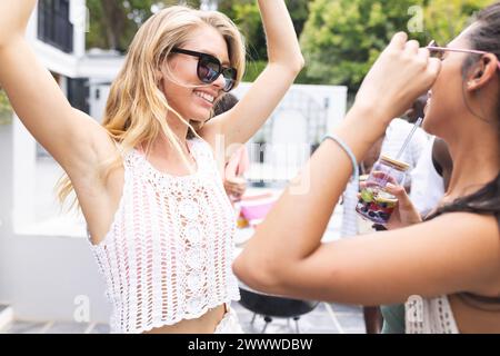 Un gruppo di giovani amici gode di un vivace raduno a bordo piscina Foto Stock