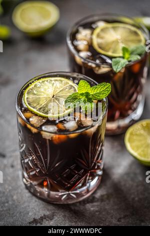 Cocktail alcolico tropicale Cuba Libre composto da rum bianco, cola, cubetti di ghiaccio, lime e menta. Foto Stock