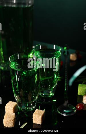 Absinthe in bicchieri da shot zucchero di canna e cucchiaio sul tavolo dello specchio. Bevanda alcolica Foto Stock