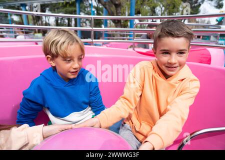 Due bambini al parco divertimenti. Amici che si divertono all'attrazione Cup Foto Stock