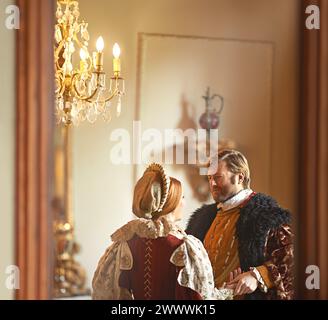 Vittoriano, uomo e donna che parlano nel castello reale insieme a un amore d'epoca, romanticismo e sala banchetti. Re medievale, regina o coppia rinascimentale Foto Stock
