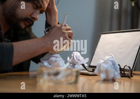 Giovane imprenditore maschio si sente esausto mentre lavora a casa. Foto Stock