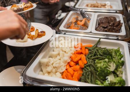 I partecipanti al seminario d'affari scelgono il cibo durante la pausa pranzo in un ristorante a buffet self-service Foto Stock