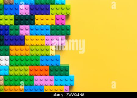 Primo piano di colorati blocchi Lego con spazio per il testo su sfondo giallo. Editoriale illustrativo Foto Stock