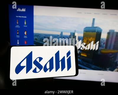 Persona che detiene uno smartphone con il logo della società giapponese Asahi Group Holdings Ltd. Davanti al sito Web. Mettere a fuoco il display del telefono. Foto Stock