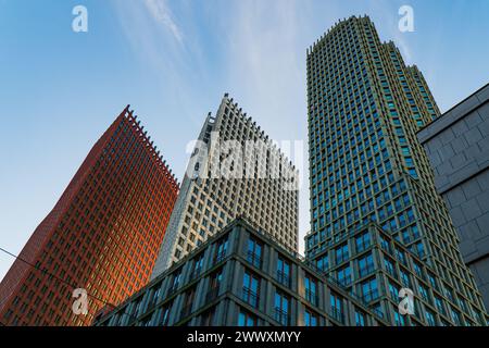 Vista verticale dei grattacieli nel quartiere centrale dell'Aia, Paesi Bassi. Luce mattutina, cielo blu con nuvole sottili. Edifici moderni e colorati. Foto Stock