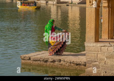 Jaisalmer, India - 22 dicembre 2023: Una donna indiana in un bellissimo vestito colorato al lago Gadisar a Jaisalmer Foto Stock