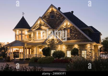 Elegante pietra grigia con rifiniture bianche e tetto blu con tegole di asfalto facciata vittoriana al crepuscolo in estate, Quebec, Canada Foto Stock