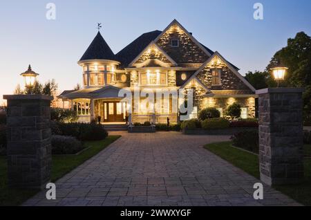 Elegante pietra grigia con rifiniture bianche e tetto blu con tegole di asfalto facciata vittoriana al crepuscolo in estate, Quebec, Canada Foto Stock