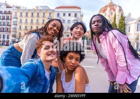 Felice e variegato, giovani amici maschi e femmine che scattano un selfie in città Foto Stock