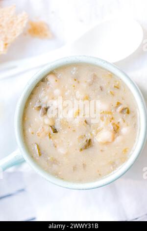 Cremosa zuppa di fagioli bianchi con cavolo e spinaci in un recipiente blu. Foto di alta qualità Foto Stock