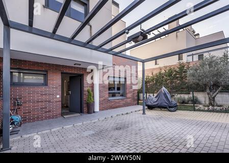 Portico d'ingresso con struttura in metallo e facciata di una moderna casa unifamiliare con splendidi giardini Foto Stock