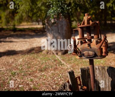 Primo piano di una pressa per uva in disuso, che mostra la sua struttura in metallo arrugginito e la base in legno Foto Stock