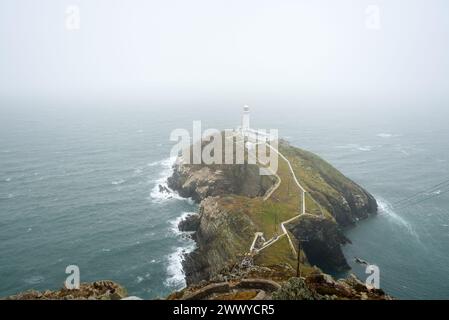 Faro storico sulla cima di una piccola isola al largo della costa del Galles in una nebbiosa giornata estiva Foto Stock