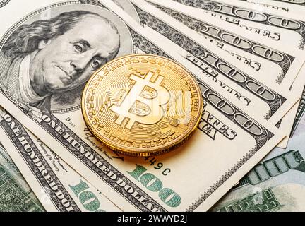 Moneta bitcoin d'oro sullo sfondo delle valute tradizionali banconote cartacee in dollari. Foto Stock